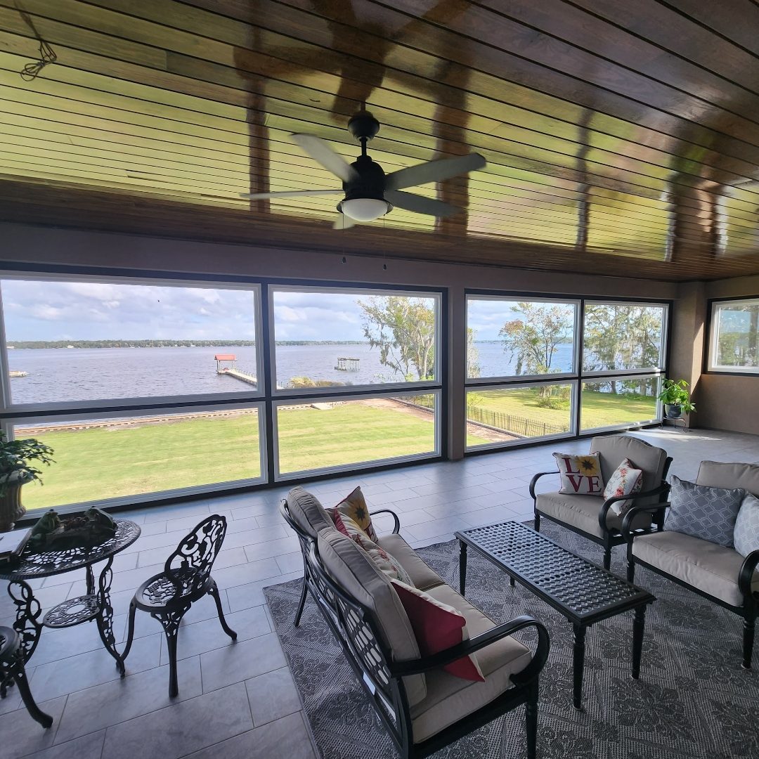 Interior of a sunroom with a wood plank ceiling and a wall of windows overlooking the river, completed by Better Home Improvement in Fleming Island, FL