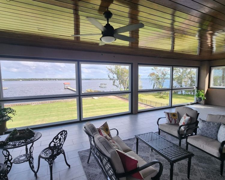 Interior of a sunroom with a wood plank ceiling and a wall of windows overlooking the river, completed by Better Home Improvement in Fleming Island, FL