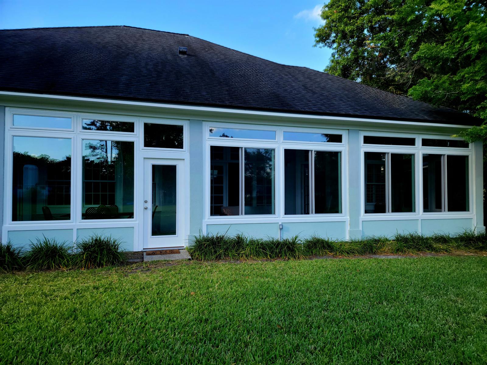 Glass sunroom addition with white-framed windows and transoms completed by Better Home Improvement in Ponte Vedra Beach, FL